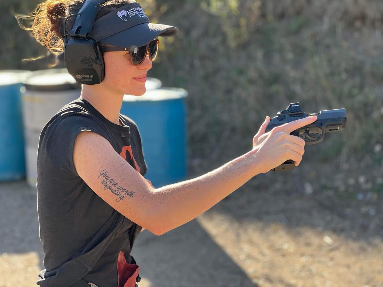 Natalee Weidner a picture of a woman smiling and safely holstering her firearm a Beretta PX 4 Storm