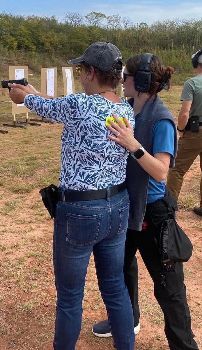 Female Firearms instructor coaching a female student on proper shooting techniques.